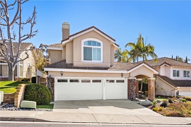 traditional home with concrete driveway, a chimney, an attached garage, and stucco siding