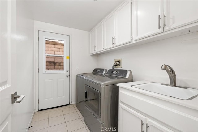 laundry room featuring cabinet space, light tile patterned floors, baseboards, washing machine and dryer, and a sink