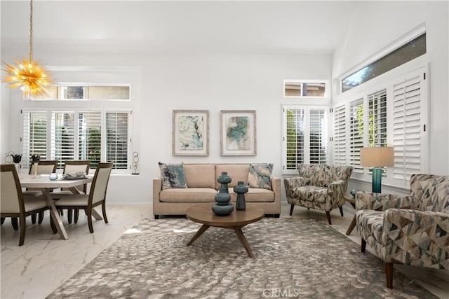 living room featuring marble finish floor, baseboards, and an inviting chandelier