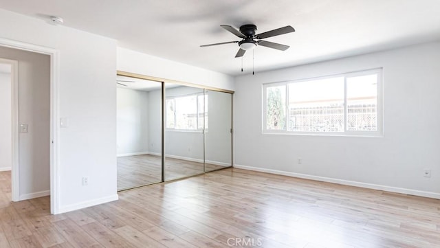 unfurnished bedroom featuring light wood-style floors, ceiling fan, baseboards, and a closet