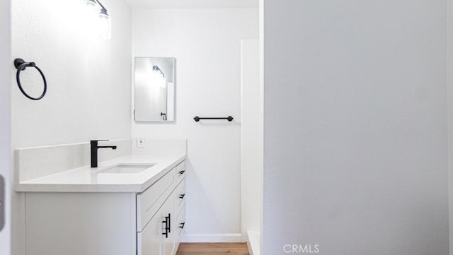 bathroom with wood finished floors, vanity, and baseboards