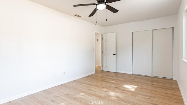 unfurnished bedroom with light wood-style flooring, a closet, visible vents, and baseboards