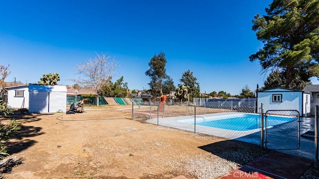 view of pool featuring a storage shed, fence, a fenced in pool, and an outbuilding