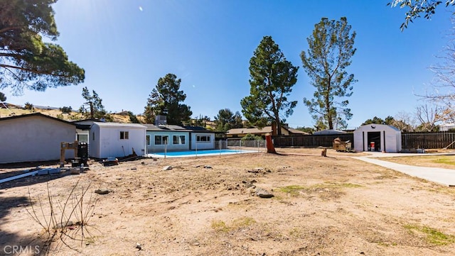 view of yard with a storage shed, a fenced backyard, a fenced in pool, and an outbuilding