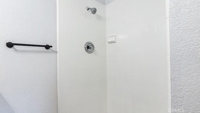 full bathroom featuring a textured wall and a tile shower