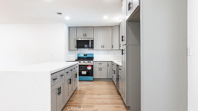 kitchen featuring light wood finished floors, visible vents, stainless steel appliances, light countertops, and gray cabinetry