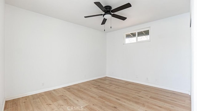 spare room featuring light wood-style flooring, baseboards, and ceiling fan