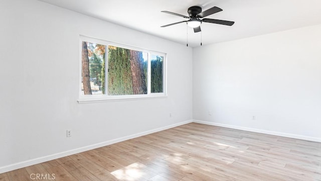 empty room featuring light wood-style flooring, baseboards, and a ceiling fan