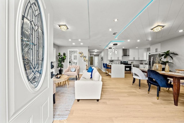 living room with light wood-style floors, visible vents, and recessed lighting