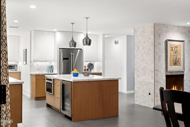 kitchen with wine cooler, a center island, hanging light fixtures, stainless steel appliances, and light countertops