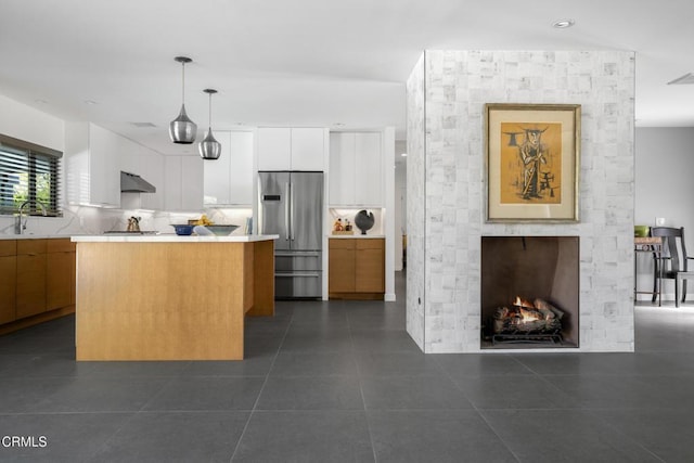 kitchen with white cabinetry, a center island, modern cabinets, stainless steel fridge, and decorative light fixtures