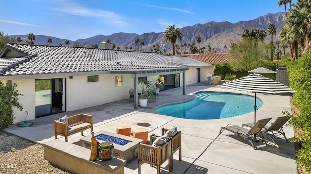 rear view of property with a patio, a mountain view, a fire pit, an outdoor pool, and a tiled roof