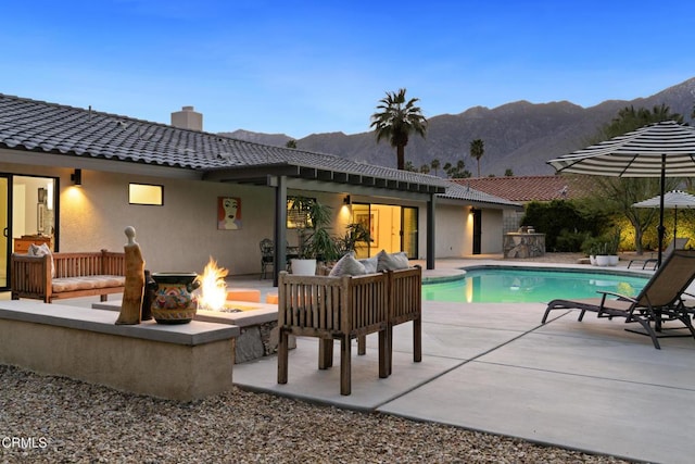 outdoor pool featuring a patio area, an outdoor living space with a fire pit, and a mountain view