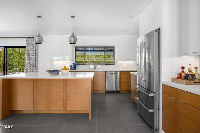 kitchen with appliances with stainless steel finishes, modern cabinets, white cabinetry, and pendant lighting