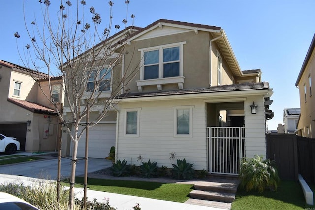 view of front of property featuring fence, a tiled roof, stucco siding, a garage, and driveway