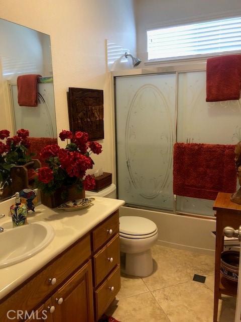 bathroom featuring shower / bath combination with glass door, vanity, toilet, and tile patterned floors