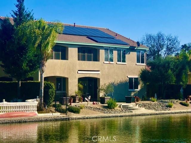 14510 Spyglass Cir, Chowchilla, CA 93610 - back of house featuring a water view, solar panels, and stucco siding