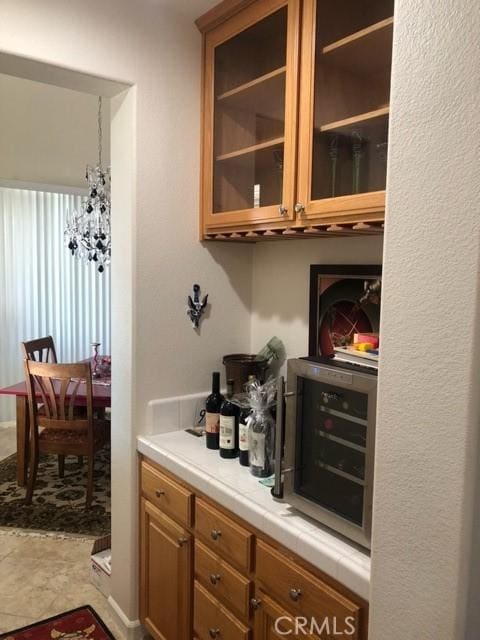 bar featuring wine cooler and a notable chandelier