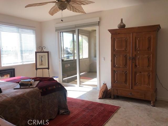 bedroom with access to exterior, ceiling fan, and light tile patterned floors