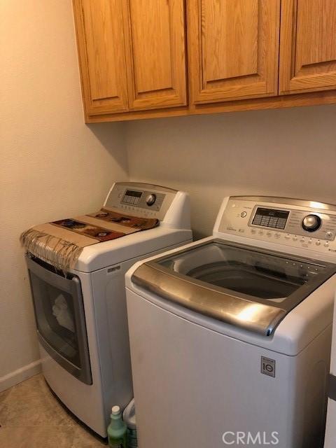 washroom featuring cabinet space, baseboards, and washing machine and clothes dryer