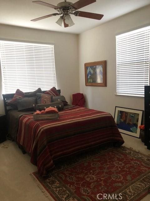 carpeted bedroom featuring a ceiling fan and multiple windows