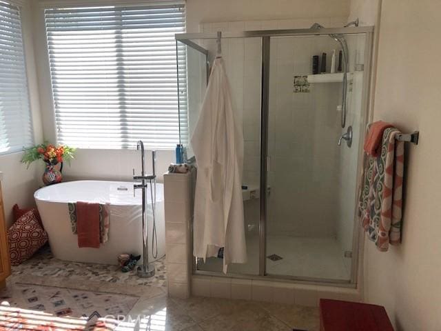 full bath with a stall shower, a freestanding bath, and tile patterned floors