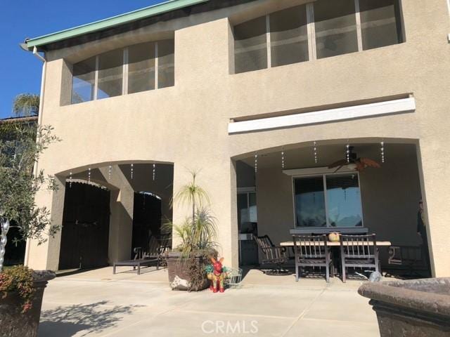 rear view of property featuring a patio area, ceiling fan, and stucco siding