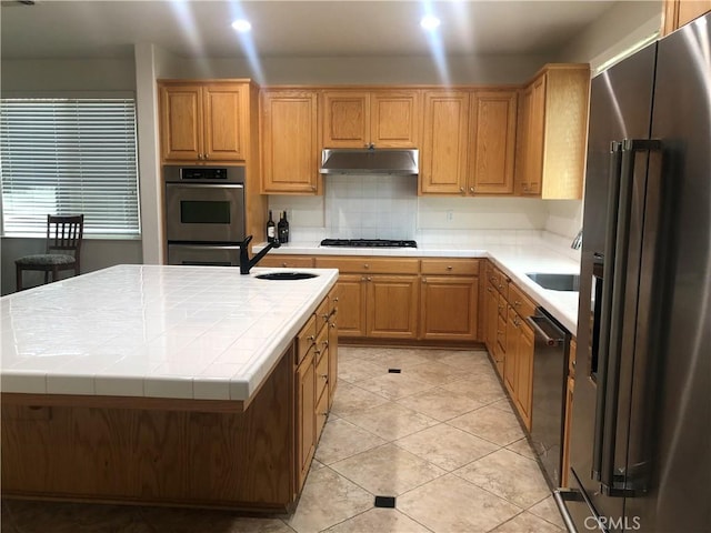 14510 Spyglass Cir, Chowchilla, CA 93610 - kitchen featuring stainless steel appliances, tile countertops, under cabinet range hood, a sink, and light tile patterned floors