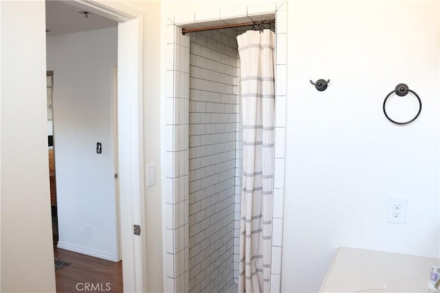 bathroom with curtained shower and wood finished floors