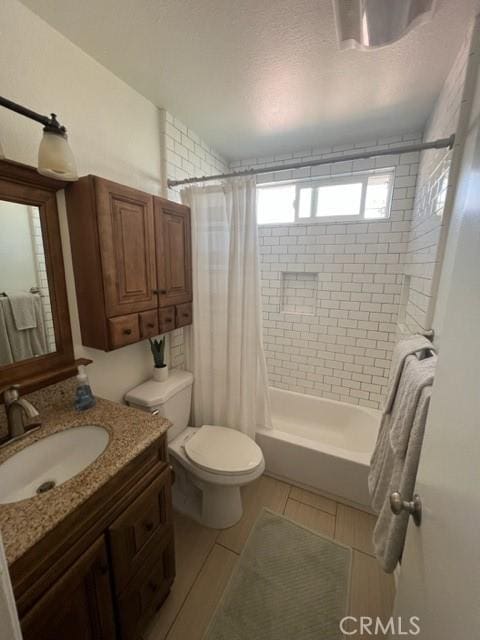 bathroom featuring shower / bath combination with curtain, vanity, toilet, and a textured ceiling