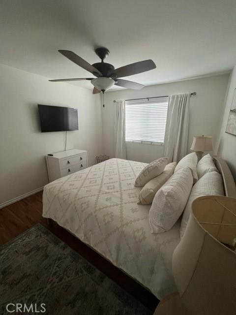 bedroom with ceiling fan, baseboards, and wood finished floors