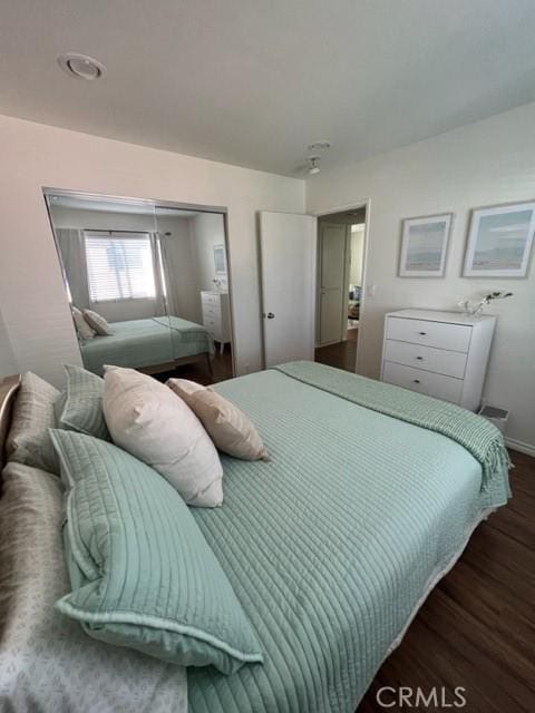 bedroom featuring dark wood-style flooring, a closet, and baseboards