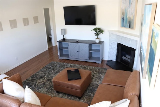 living area with a high end fireplace, dark wood finished floors, and baseboards