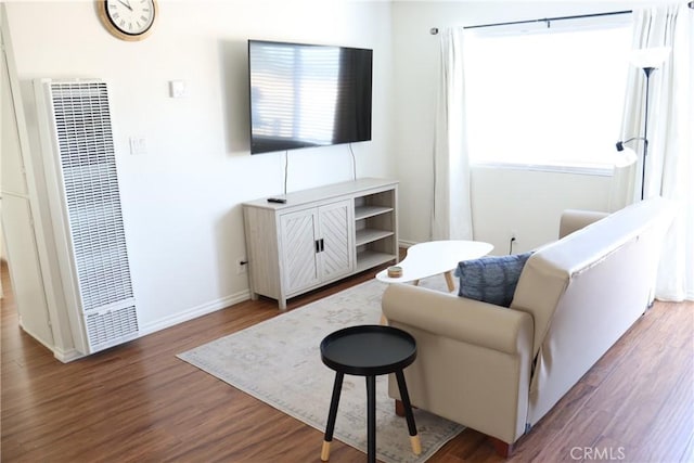 living area with dark wood-style flooring, a heating unit, plenty of natural light, and baseboards