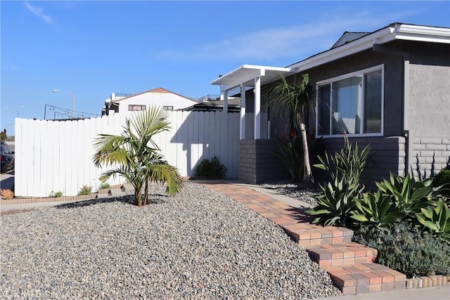 view of side of home featuring fence and stucco siding