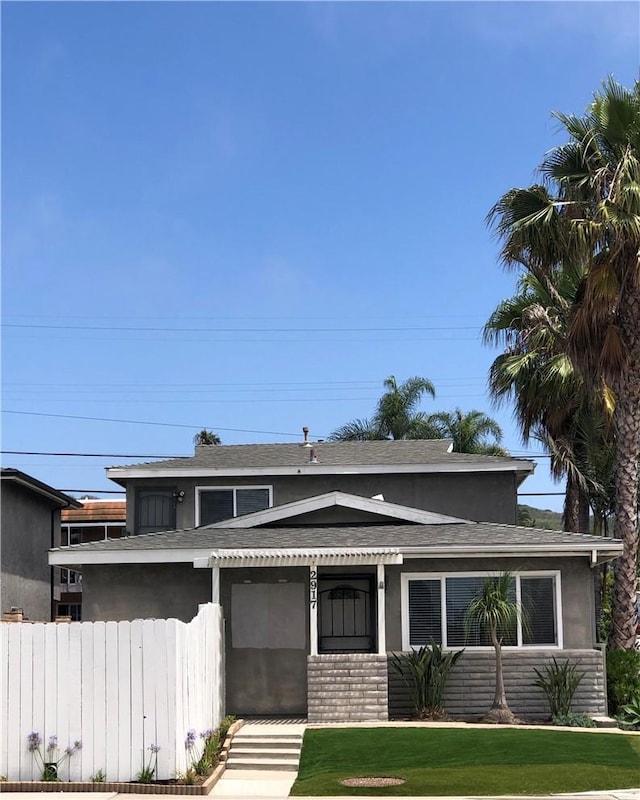 view of front of home featuring fence, a front lawn, and stucco siding