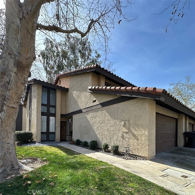 view of home's exterior with concrete driveway, a yard, an attached garage, and stucco siding