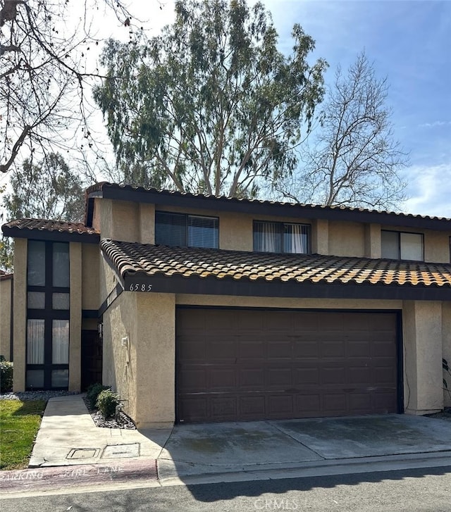 multi unit property featuring a garage, a tile roof, driveway, and stucco siding