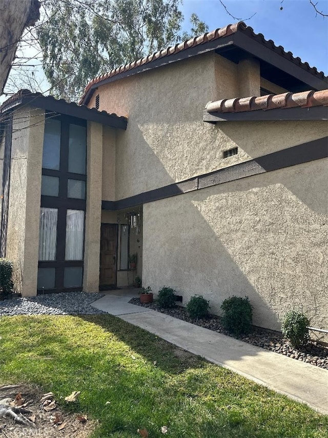 view of side of home with a lawn and stucco siding