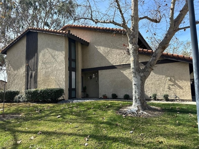 view of side of property with stucco siding and a yard