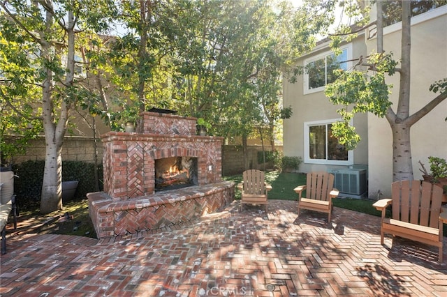 view of patio with an outdoor brick fireplace, cooling unit, and fence