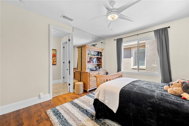 bedroom with visible vents, ceiling fan, baseboards, and wood finished floors