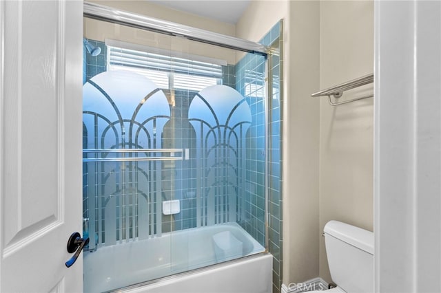 bathroom featuring combined bath / shower with glass door and toilet