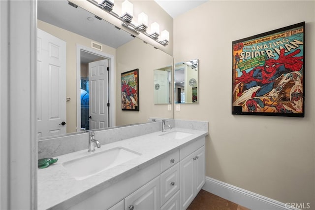 bathroom with double vanity, baseboards, visible vents, and a sink