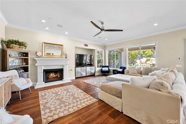 living room with a glass covered fireplace, wood finished floors, visible vents, and crown molding