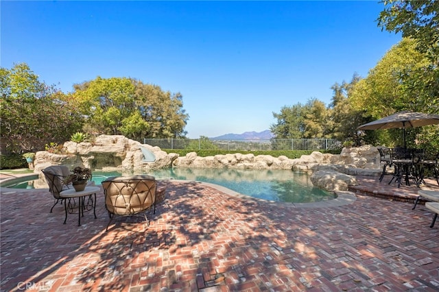 view of swimming pool featuring a fenced in pool, a water slide, a patio area, and fence