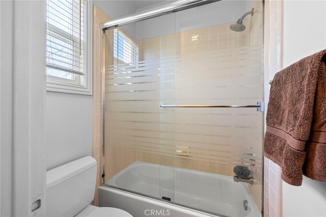 bathroom with combined bath / shower with glass door and toilet