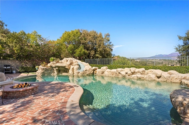 view of pool featuring a fire pit, a fenced in pool, a grill, fence, and a patio area