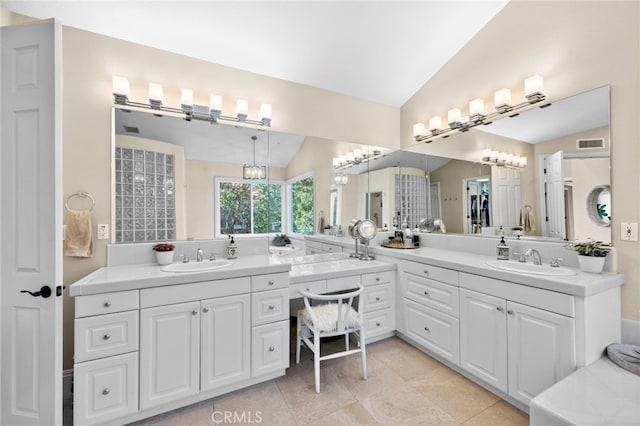 bathroom with lofted ceiling, visible vents, two vanities, and a sink