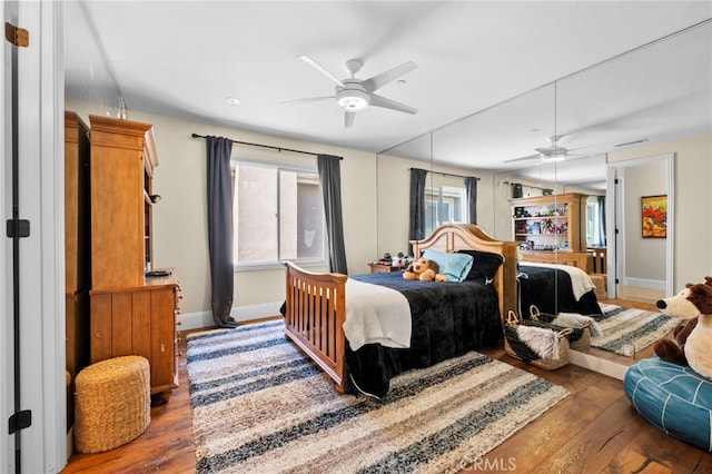 bedroom featuring multiple windows, wood finished floors, and baseboards